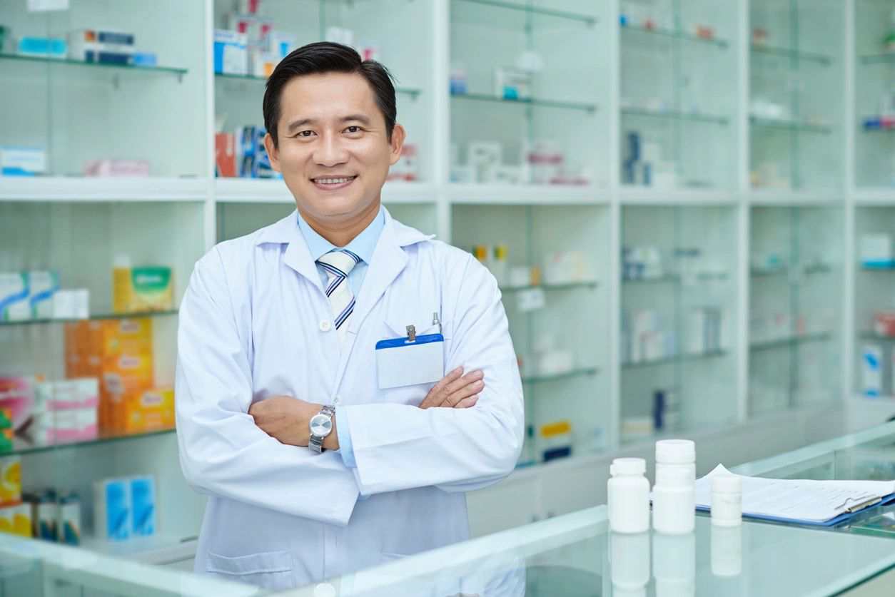 A man in white lab coat standing next to shelves.